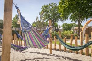 a boy is sitting in two hammocks on a playground at Vakantiepark De Boshoek in Voorthuizen