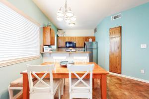 a kitchen with a wooden table and white chairs at Lyla's Beach Getaway in Padre Island