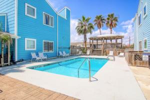 a swimming pool in front of a blue house at Lyla's Beach Getaway in Padre Island