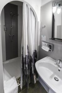 La salle de bains est pourvue d'un lavabo et d'une douche avec rideau de douche. dans l'établissement Hôtel Brasserie du Parc, à Albi