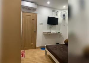 een kamer met een bed, een televisie en een deur bij D Home in Ho Chi Minh-stad