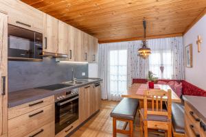 una cucina con mobili in legno, tavolo e piano cottura di Ferienwohnung am Baby & Kinderbauerhof Stefflhof a Saalfelden am Steinernen Meer