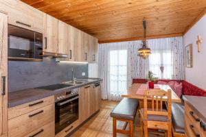 a kitchen with wooden cabinets and a table and a kitchen with a stove at Ferienwohnung am Baby & Kinderbauerhof Stefflhof in Saalfelden am Steinernen Meer