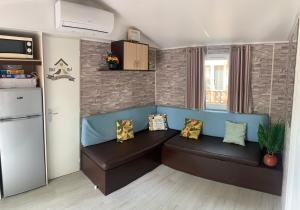 ein Wohnzimmer mit einem Sofa und einem Kühlschrank in der Unterkunft Mobil home « lysea », 6p, Clim in Agde