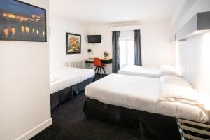 a hotel room with two beds and a desk at Hôtel Brasserie du Parc in Albi