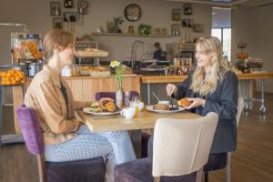 Duas mulheres sentadas à mesa a comer comida. em Vakantiepark De Boshoek em Voorthuizen