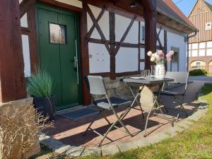 a patio with a table and chairs and a green door at Ferienhaus Oberlausitz in Cunewalde