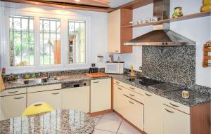 een keuken met witte kasten en granieten aanrechtbladen bij 3 Bedroom Cozy Home In Vic-en-bigorre in Vic-en-Bigorre