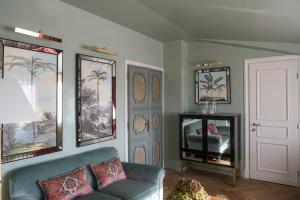 a living room with a couch and palm trees on the wall at Hotel d’Inghilterra Roma – Starhotels Collezione in Rome