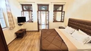 a bedroom with a bed and a table and windows at Citadel Resort in Panchgani