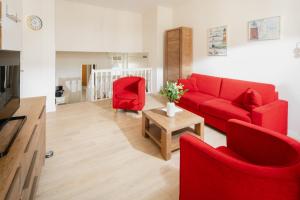 - un salon avec un canapé rouge et deux chaises dans l'établissement Strandloge, à Norderney