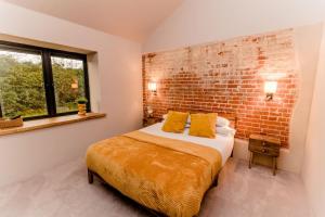 a bedroom with a bed and a brick wall at Beautiful Barn Conversion Close To The Broads in Dilham