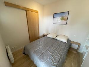 1 dormitorio pequeño con 1 cama y una foto en la pared en Les terrasses de l'océan A11, en Mimizan
