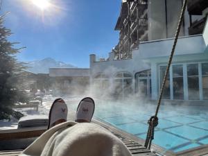 a person sitting on a swing in front of a pool at Superior Sport und Familienresort Alpenblick in Zell am See