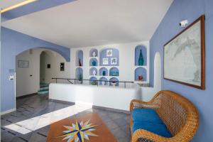 Maresca Hotel Praiano في برايانو: غرفة معيشة مع جدران زرقاء وكرسي الخوص