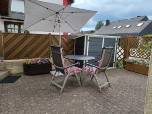 a table and two chairs with an umbrella on a patio at Ferienwohnung Fischer in Konz
