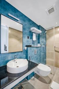 a bathroom with a sink and a toilet and a mirror at Regency Tuticorin by GRT Hotels in Tuticorin