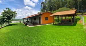 uma pequena casa com um quintal relvado ao lado de um edifício em Pesqueiro Rancho Feliz em Fama