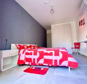a bedroom with a red and white bed and a desk at Central Private En-Suite with Balcony in shared residence in Tal-Pietà