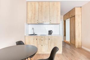 eine Küche mit Holzschränken und einem Tisch und Stühlen in der Unterkunft New Gudauri, Alpic - Ski Resort at Your Doorstep - Stylish & Comfy Ski Apartment with ski-depot and Stunning Mountain Views in Gudauri