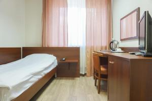 a bedroom with a bed and a desk with a television at City Hotel in Yekaterinburg