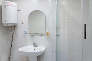 uma casa de banho branca com um lavatório e um chuveiro em City Hotel em Ecaterimburgo