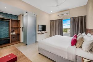 sypialnia z dużym białym łóżkiem i telewizorem z płaskim ekranem w obiekcie Regency Tuticorin by GRT Hotels w mieście Tuticorin