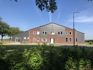 un grand bâtiment en briques et gris dans un champ dans l'établissement Mysa, à Deurne