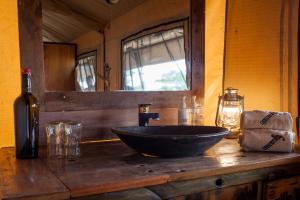 a bathroom with a bowl sink on a wooden counter at Baobab Tented Camp in Kwa Kuchinia