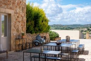 a patio with tables and chairs and a stone wall at I Carusi Relais in Noto