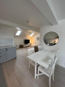 a white dining room with a white table and a mirror at Nice Apartment close to everything in Malmö