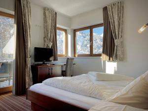 a bedroom with a bed and a tv and windows at Hotel Garni Philipp in Serfaus