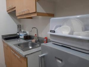 a kitchen with a sink and a dish rack with plates at Comfy Bunkbeds at BSA in Manila