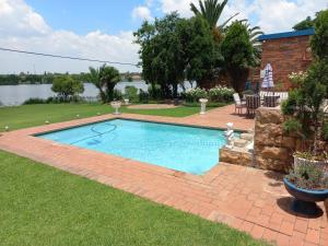 a swimming pool in a yard next to a body of water at The Lakehouse BnB in Brakpan