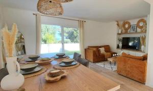 a dining room with a wooden table and a living room at Villa Junna in Fréjus