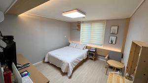 a bedroom with a bed and a desk and a window at Tongyeong Chosun Hotel in Tongyeong