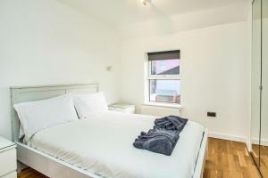 1 dormitorio con cama blanca y ventana en Pebble Cottage, en Ventnor