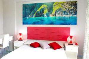 ポンツァにあるホテル　オルテンシアの赤いヘッドボードと壁画が備わるベッドルーム