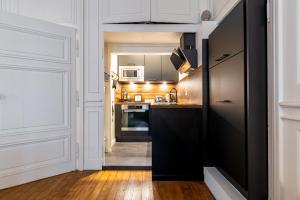 a kitchen with white cabinets and a black refrigerator at L' ALCOVE- Confort Charme Downtown in Dijon
