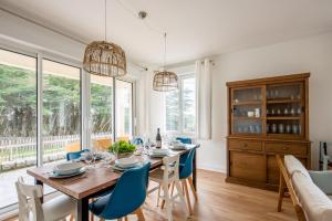 a dining room with a wooden table and blue chairs at Les Roches Plates in Fréhel