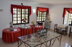 a room with two tables with red table cloths and windows at Pousada das Rosas in Miguel Pereira
