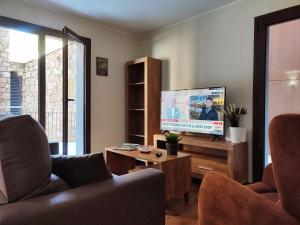 salon z telewizorem z płaskim ekranem i 2 krzesłami w obiekcie AC Apartaments Bordes w mieście Bordes d´Envalira 