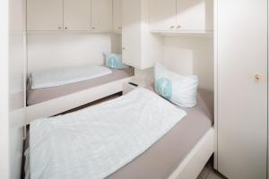 - 2 lits dans une petite chambre avec des armoires blanches dans l'établissement Studio 10 Damenpfad 32, à Norderney