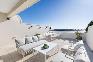 a patio with a couch and tables on a balcony at Panoramic Water View Apartment in Sylvania