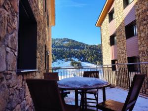 a table and chairs on a balcony with snow on it at AC Apartaments Bordes in Bordes d´Envalira 