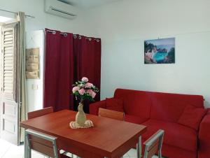 a living room with a table and a red couch at Don Vito's Apartments in Castellammare del Golfo