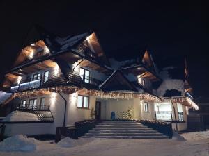 Un edificio con le luci di Natale sulla neve di CIABAS Apartamenty a Białka