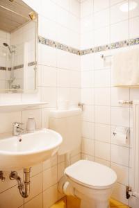 a white bathroom with a toilet and a sink at Gasthof Schattleitner in Brückl