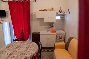 uma pequena cozinha com uma mesa e uma cortina vermelha em Casa Lucrezia em Ostuni