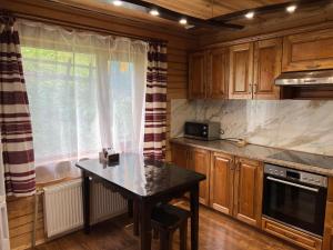 a kitchen with wooden cabinets and a table in it at Котедж Mezohat in KozÊ¼meshchek